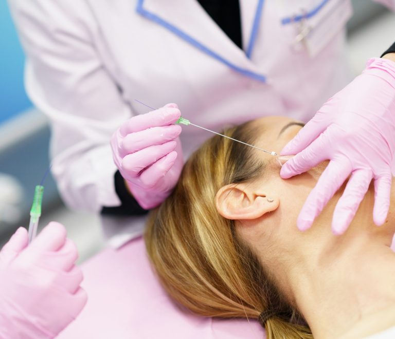 Doctor injecting PDO suture treatment threads into the face of a woman