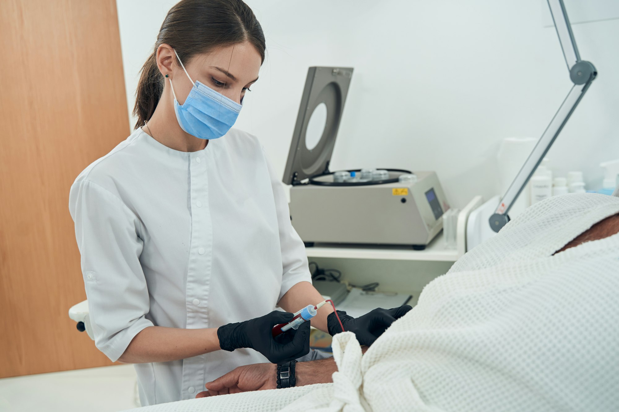 Doctor taking blood sample from patient in clinic