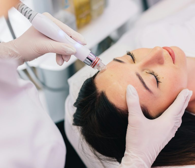 Cosmetologist doing hydrafacial treatment on woman face