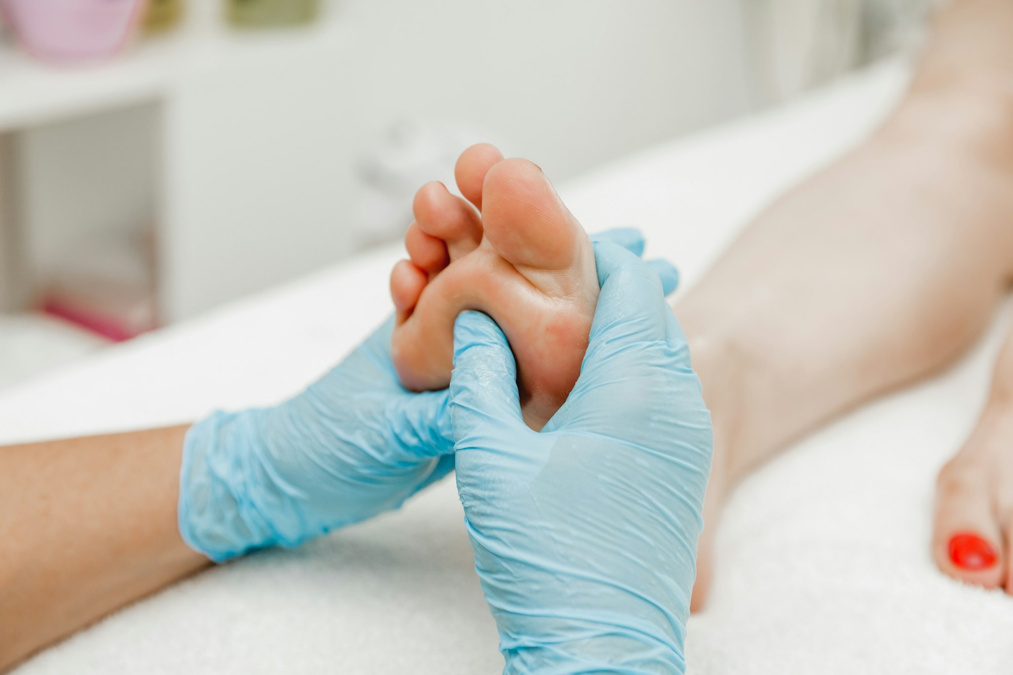 Foot massage in a spa salon, close-up. masseur with gloves massages feet