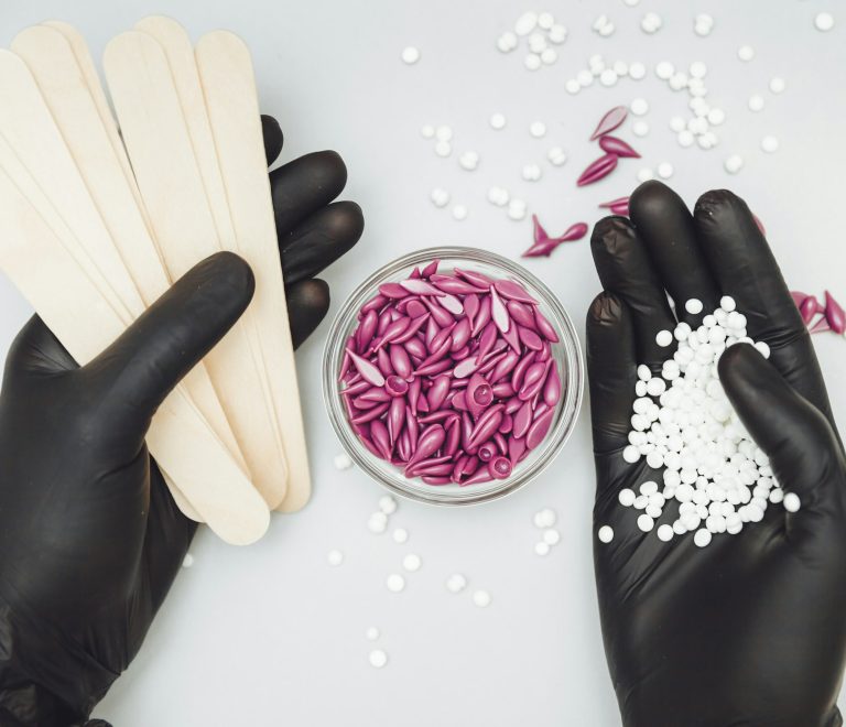 Wax granules in the hand of a cosmetologist girl. Spatula and wax in hand. Body hair removal wax.