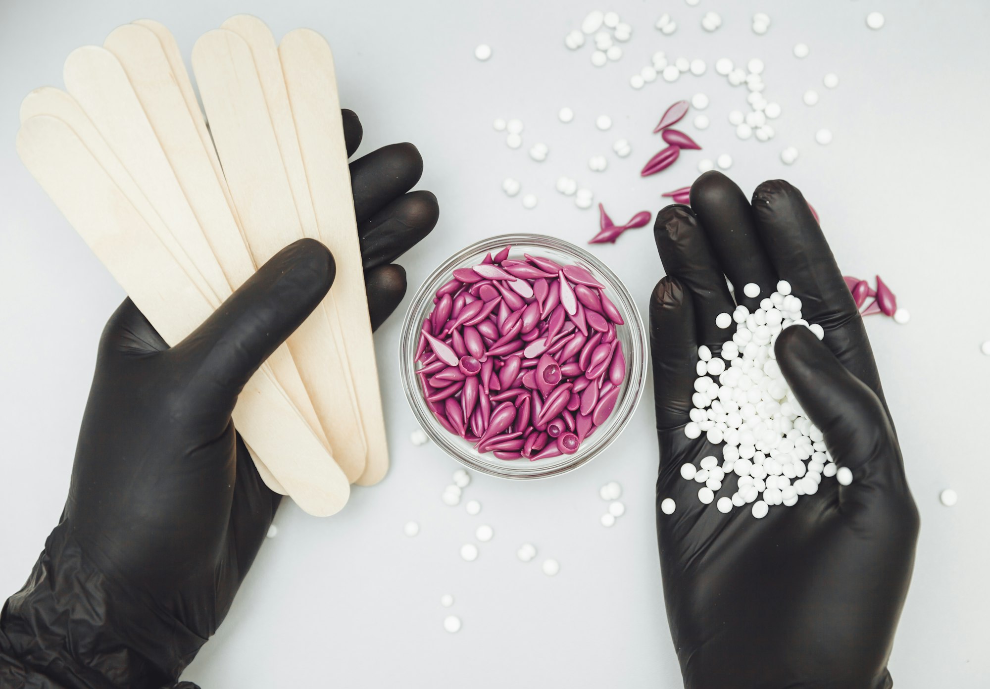 Wax granules in the hand of a cosmetologist girl. Spatula and wax in hand. Body hair removal wax.